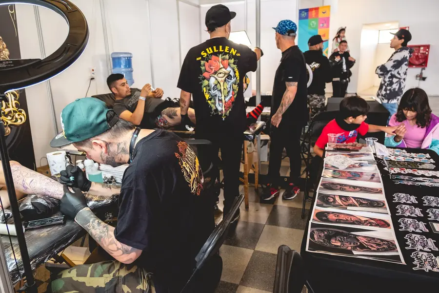 Tatuadores trabajando en sus stands durante la expo de tatuajes